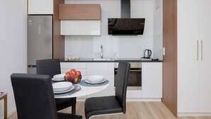 A compact kitchen with a built-in oven, a microwave, and a stainless steel refrigerator. - Bright Apartment with Parking and Balcony | Close to the Airport (Warszawa)