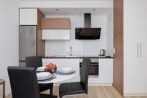 A compact kitchen with a built-in oven, a microwave, and a stainless steel refrigerator. - Bright Apartment with Parking & Balcony Close to the Airport (Warszawa)