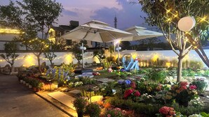 Un jardín con plantas en macetas, una zona de juegos y una tienda de campaña.