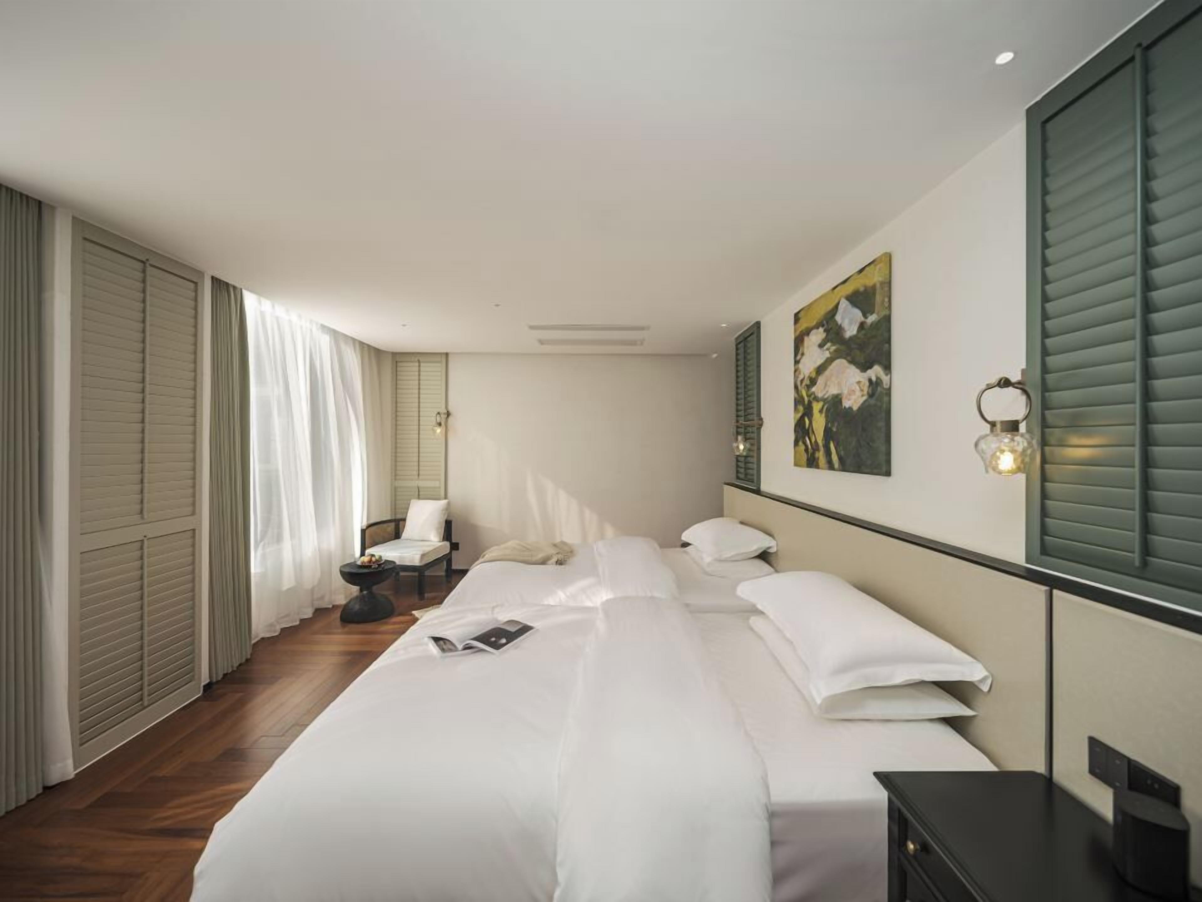 Habitació d'hotel amb un llit gran, una taula de nit, una cadira, un escriptori i un quadre a la paret.
