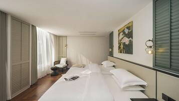 Habitació d'hotel amb un llit gran, una taula de nit, una cadira, un escriptori i un quadre a la paret.