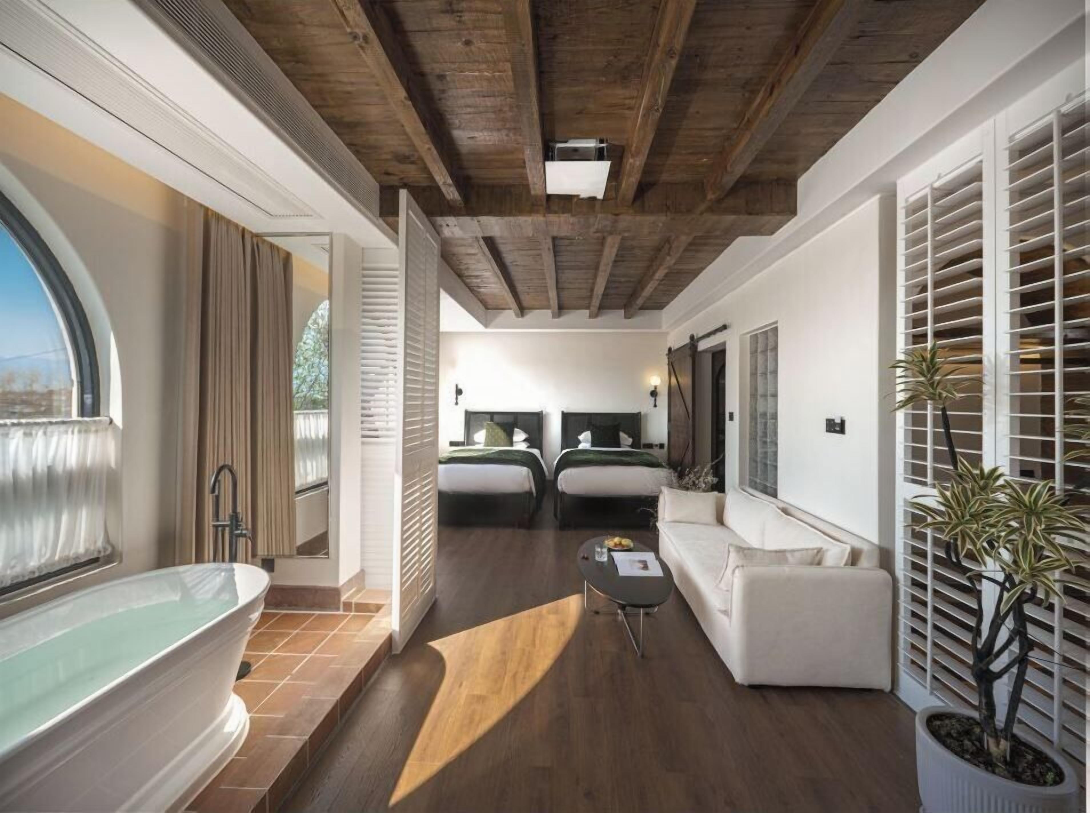 Un interior moderno con una bañera grande, dos camas, un sofá y una planta en maceta.
