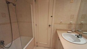 Un bagno con doccia, lavandino e specchio.