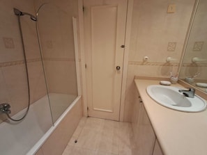 Une salle de bain avec une douche, un lavabo et un miroir.