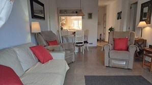 Un soggiorno con divano, poltrone, un tavolo da pranzo e un'area cucina sullo sfondo.