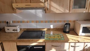 Una cucina attrezzata con fornello, tostapane, bollitore, forno a microonde e scolapiatti.