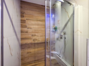 Ein Duschbereich mit Glastür, Holzboden und einer Glasdusche.