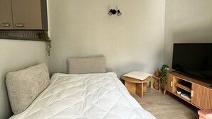 A bedroom with a bed, a TV, a small table, and a cabinet. - Renovated T2 - Cathedral view - Center - Wifi (Lodève)
