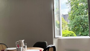 A dining area with a table, chairs, a pitcher, and a window with a view of greenery. - Renovated T2 - Cathedral view - Center - Wifi (Lodève)