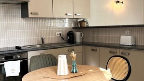 A modern kitchen with a round dining table, chairs, a coffee maker, and a kettle. - Renovated T2 - Cathedral view - Center - Wifi (Lodève)