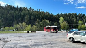 Un parking avec un autobus rouge, un banc et une voiture blanche.