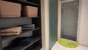 Ett modernt badrum med en duschkabin i glas, en handdukshängare och en grön matta.