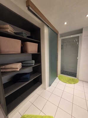 Ein modernes Badezimmer mit Duschkabine aus Glas, einem Handtuchhalter und einer grünen Matte.