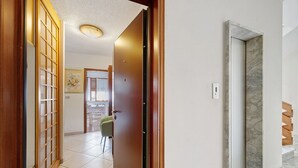 Ein Flur mit einer Holztür, einem Fliesenboden und einer Treppe mit Marmorstufen.