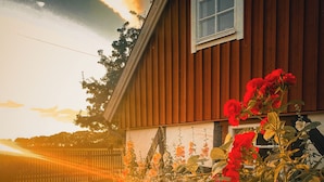 A wooden house with a window, surrounded by a fence and blooming red flowers. - Gorgeous and cosy 3-bedroom house in beautiful landscape. (Helsingborg)