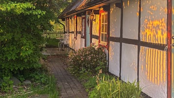 Un bâtiment traditionnel avec un toit en pente, un chemin menant à l’entrée et une clôture en arrière-plan.