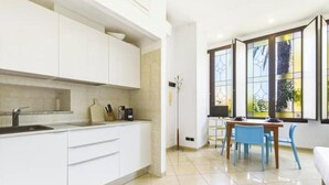 Una cucina moderna con mobili bianchi, un lavello e un'area pranzo con sedie blu e un tavolo.