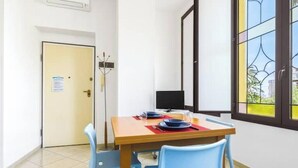 Un'area pranzo con tavolo apparecchiato per due, televisione e una porta con un cartello.