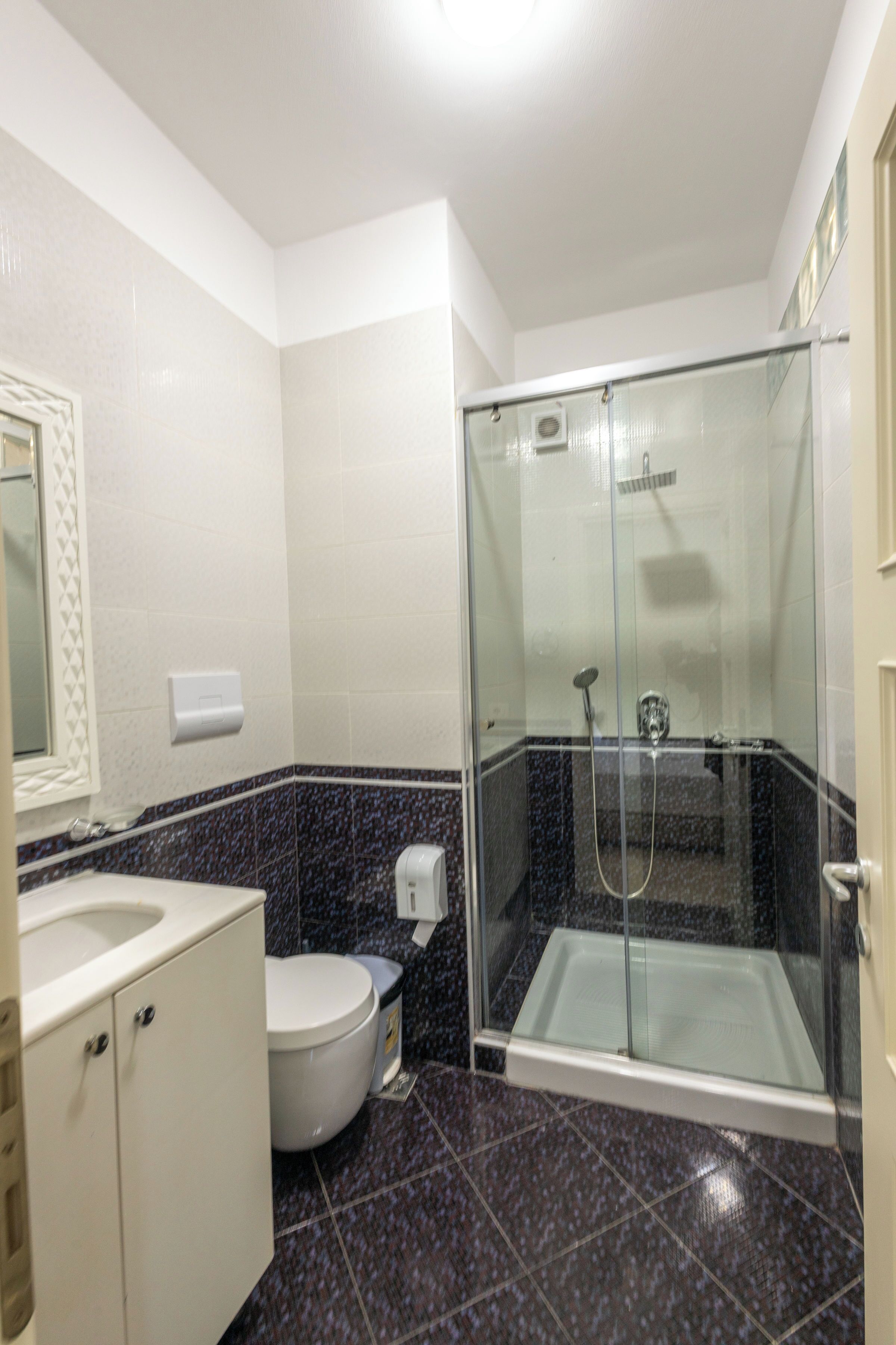 Un baño con ducha envuelta en vidrio, inodoro y lavamanos.