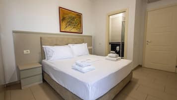 Ein Hotelzimmer mit einem Bett, einem Nachttisch, einem Gemälde, einem Spiegel und einer Tür.