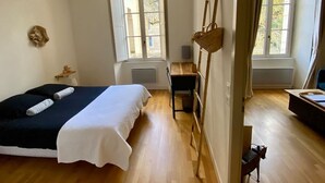 Un dormitorio con cama, escritorio, silla y una cesta colgante.