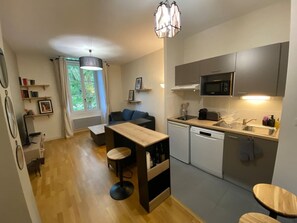 A compact kitchen with a dining area, a built-in microwave, and a dishwasher. - Au Fil du Clain - Cosy T2, parking & fiber (Poitiers)