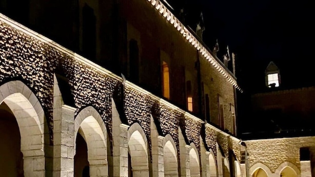 Un edificio con varios arcos de entrada y una serie de luces a lo largo del borde del techo.
