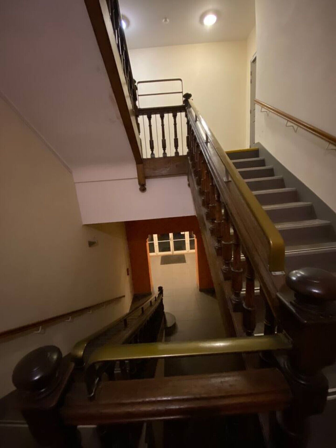 A staircase with wooden handrails and a metal banister, leading to an upper floor.