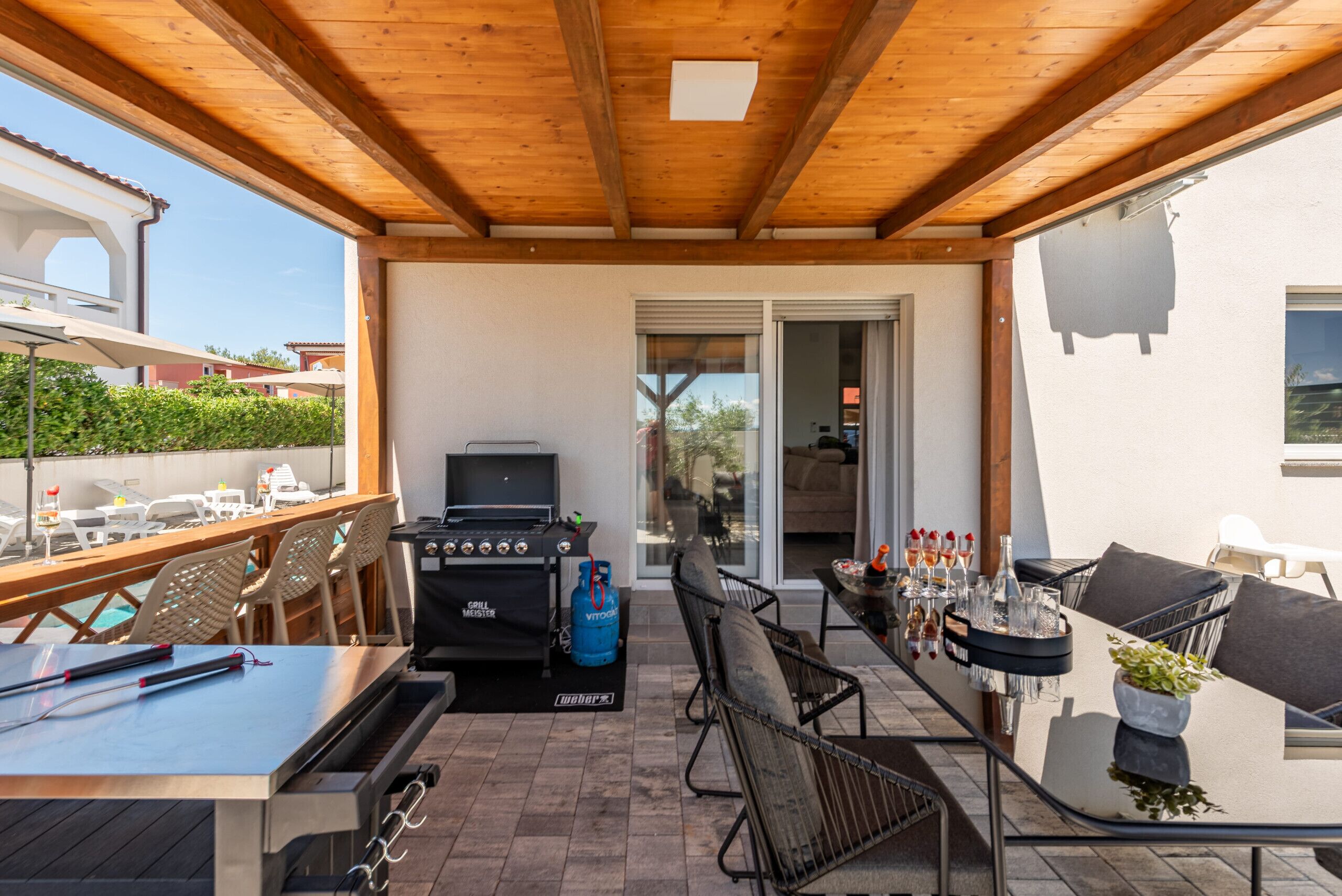 An outdoor patio with a grill, seating, and a view of the neighborhood.
