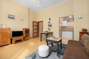 Ein Wohnzimmer mit Fernseher, Holzmöbeln, einer Essecke und einer Küche.