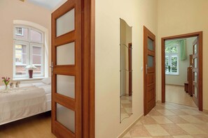 Ein Schlafzimmer mit Bett, Fenster, Tür und einem Flur zu einem weiteren Raum.