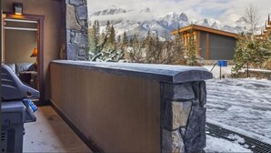 A hotel room with a stone wall, a wooden ceiling, and a view of snow-covered mountains. - Spring Creek Courtyard Retreat | Hot Tub, Pool Table & Trailside Access (Canmore)