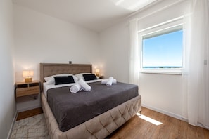 Ein Schlafzimmer mit Bett, Nachttischen, einem Fenster mit Aussicht und Holzboden.
