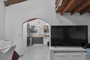 A modern kitchen with white cabinets, a large TV, and a wooden ceiling. - ☀️ In the heart of Rue Meynadier & Palais (Cannes)