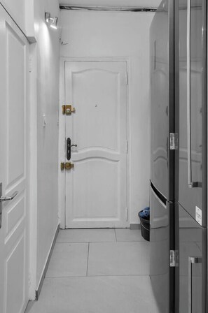 A narrow hallway with a white door, a trash bin, and a refrigerator. - ☀️ In the heart of Rue Meynadier & Palais (Cannes)