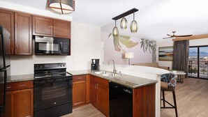 Une cuisine moderne avec des meubles en bois, un four encastré, un lave-vaisselle et un grand îlot central doté d’un évier.