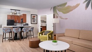 Un salon moderne avec une table ronde, un canapé, un coin repas avec des chaises et une cuisine en arrière-plan.