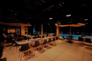 Un comedor interior con mesas y sillas, una piscina y una zona de bar.