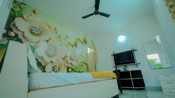 A bedroom with a bed, a ceiling fan, a TV, and a window.