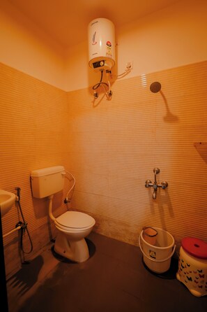 Un baño con inodoro, bidé, un cubo y calentador de agua.