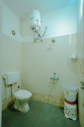 Un baño pequeño con inodoro, calentador de agua y un balde.