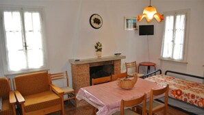 Ein Zimmer mit Kamin, einem Esstisch mit Stühlen, einer Couch, einem Bett und einem Fernseher.