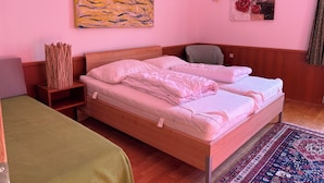 Una habitación con una cama de madera, un sofá verde, un tapiz estampado y dos obras de arte en las paredes.
