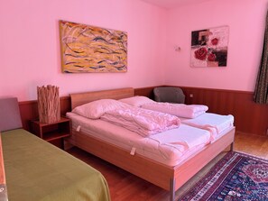Ein Zimmer mit einem hölzernen Bett, einem grünen Sofa, einem gemusterten Teppich und zwei Wandbildern.