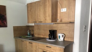 Una cocina con armarios de madera, una encimera, una cafetera, un hervidor y un grifo.