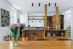 A modern kitchen with wooden cabinets, a central island, and a dining area with a wooden table and chairs. - Terraced house in Komponistkvarteret, Østerbro (København)