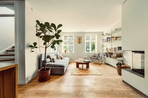 A modern living room with a sofa, coffee table, bookshelf, and a large potted plant. - Terraced house in Komponistkvarteret, Østerbro (København)