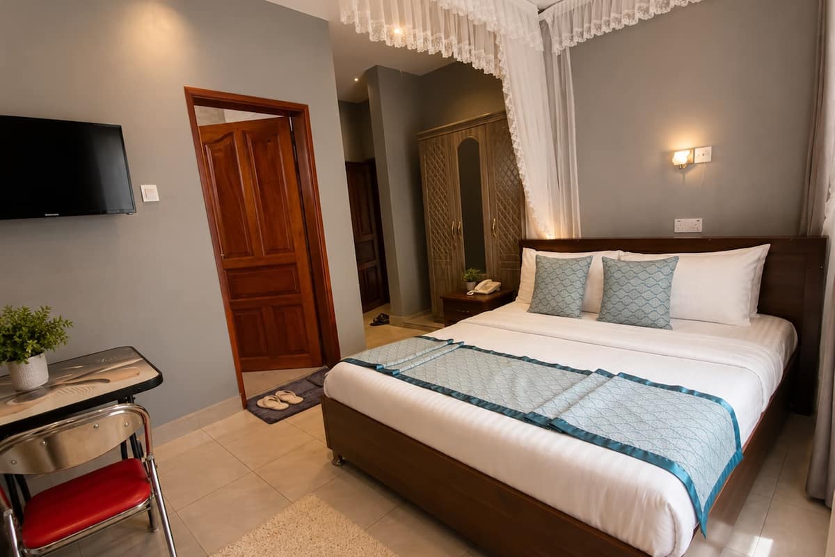 Una habitación de hotel con cama, mesita de noche, silla, televisión y armario.