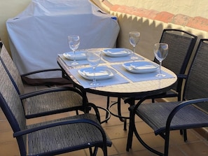 A table set for four with wine glasses and plates, surrounded by wicker chairs. - Duquesa Village El Hacho (Manilva)