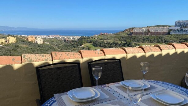 Ein Tisch für zwei Personen mit Blick auf das Meer und Gebäude im Hintergrund.